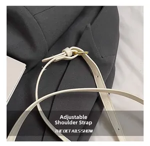 Detail of adjustable white leather shoulder strap with gold buckle on woven handbag