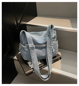 Dettaglio borsa a tracolla in denim lavato blu con ampia tracolla regolabile e tasche