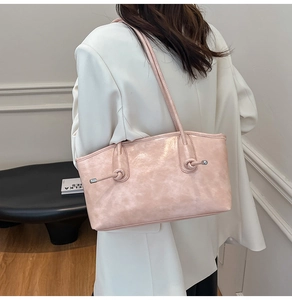 Détail d'un sac cabas rose poudré avec texture marbrée et nœud décoratif sur la bandoulière