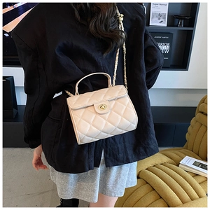 Quilted crossbody bag in beige leather with golden chain and handle shown on model