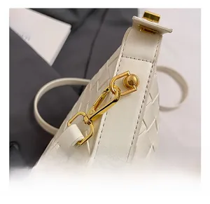 Close-up of white woven leather texture with a premium gold-toned metallic twist lock hook