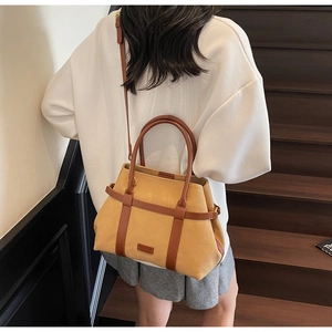 Borsa tote in tela giallo senape con cinturini in pelle marrone indossata su felpa bianca
