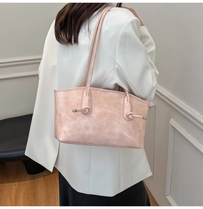 Détail d'un sac cabas rétro rose avec décoration de nœud porté à l'épaule d'un mannequin