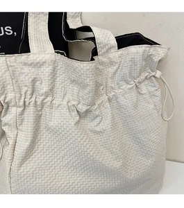 Dettaglio della borsa tote a scacchi in nylon con cuciture rifinite e chiusura a cordoncino