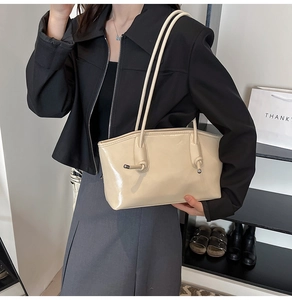 Détail d'un sac sous le bras beige brillant avec bandoulière nouée et accents métal