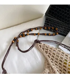 Detail view of woven straw tote bag featuring beaded shoulder straps and crochet mesh texture