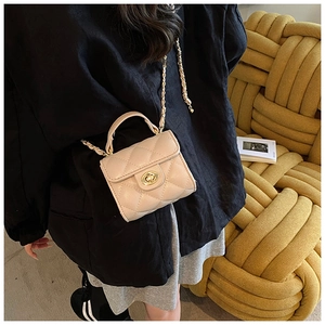 Detail of beige quilted mini crossbody bag with gold lock and chain strap