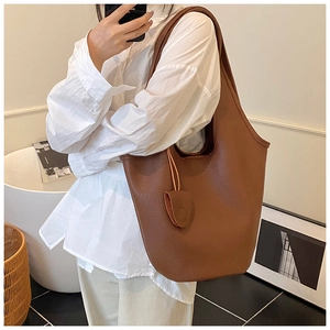 Brown litchi grain leather hobo shoulder bag shown on model in a cozy interior setting