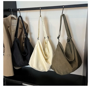 Vista detallada de bolsos hobo de lona en negro, crema y verde oliva en soporte