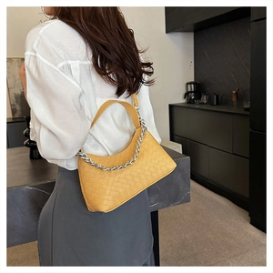 Detail view of mustard yellow woven hobo bag with a silver chain and shoulder strap