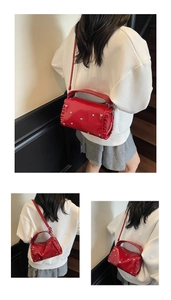 Detail of red leather crossbody bag featuring silver heart studs and ruffled side design