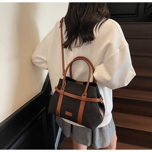 Détail du sac seau en toile avec lanières en cuir marron et boucles dorées sur l'épaule