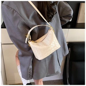 Close-up of white woven shoulder bag with gold hardware and adjustable strap detail