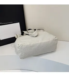Dettaglio della grande borsa tote intrecciata color crema con un design minimalista