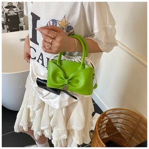 Détail du sac à main vert fluo avec nœud, doublure à cordon et breloque en forme de cœur