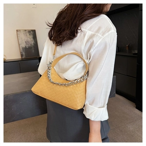 Detail of yellow woven hobo bag with chunky silver chain and sleek leather strap