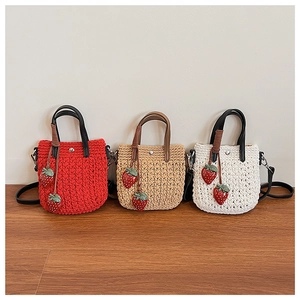 Détail de sacs à main tissés colorés avec des breloques fraises 3D et des anses en cuir