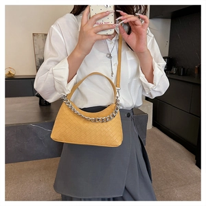 Detail shot of a yellow woven dumpling bag with silver chain and leather strap
