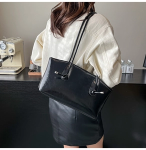 Détail d'un sac cabas en cuir verni noir avec des boucles à nœuds en métal argenté