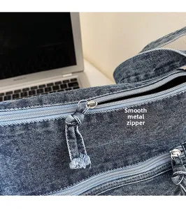 Detail of smooth metal zipper and internal pocket on blue denim tote bag