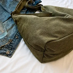 Detalle de bolsa de lona verde militar sobre sábana blanca con estilo casual diario