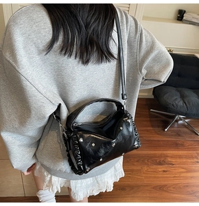 Detail of black pillow bag with silver heart studs and pleated wave edges on a person