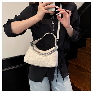 Detail of cream woven leather handbag with silver chain and wide handle shown on model