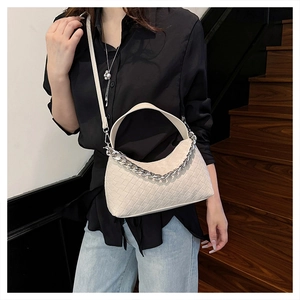 Detailed view of beige woven leather dumpling bag with silver chain strap on model