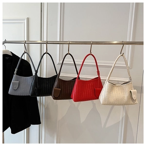 Close-up of elegant woven underarm bags in five colors hanging on a metal rack