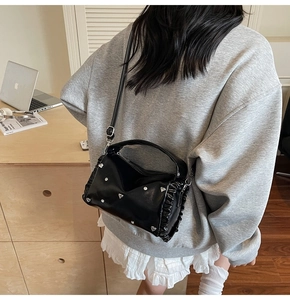 Detail of ruched black tote bag with silver heart studs shown in casual commute styling