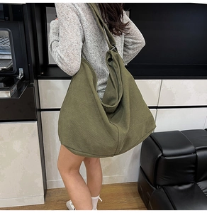Bolso tote grande de lona verde oliva con silueta relajada sobre el hombro del modelo