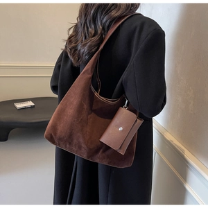 Detail of a large brown suede hobo bag with matching pouch shown on a model