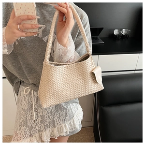 Detailed close-up of cream woven shoulder bag texture with artisanal crisscross pattern