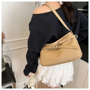 Close-up of khaki shoulder bag featuring unique vertical pleats and silver metal hardware
