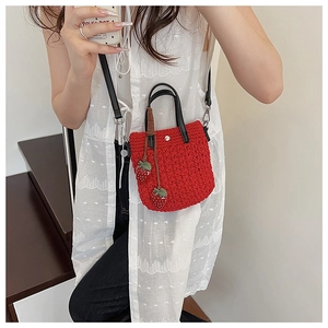 Détail du mini sac crochet rouge avec charms fraises et bandoulière sur modèle