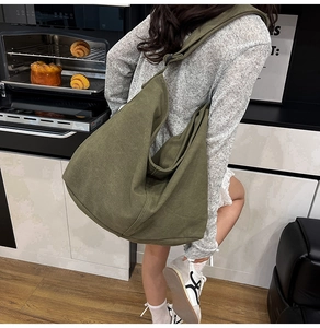 Vista detallada del bolso hobo de lona verde oliva con correa ancha y textura de tela