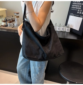 Primer plano de un bolso tote grande de lona negra estilo hobo en una cafetería relajada