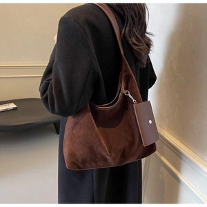 Detail of a dark brown suede tote bag with a detachable mini pouch and silver ring