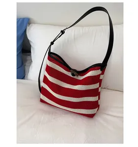 Detail of red and white striped knit tote bag with leather strap and wooden toggle closure