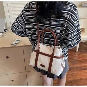 Dettaglio della borsa tote in tela con finiture in pelle marrone e tracolla regolabile