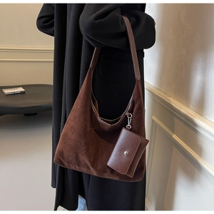 Detailed close-up of dark brown suede hobo bag with leather strap and mini pouch charm