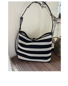 Detail of striped woven tote bag with wooden buckle closure and adjustable leather strap