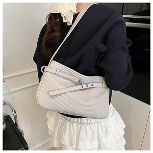 Detail of off-white shoulder bag with vertical embossed texture and decorative buckle