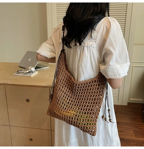 Detail of straw tote bag featuring mesh knit design and beaded shoulder straps