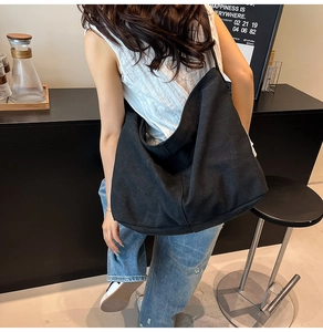 Primer plano del bolso hobo de lona negra mostrando su diseño espacioso y resistente