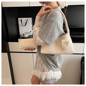 Detail of cream woven leather underarm bag and matching pouch showing texture