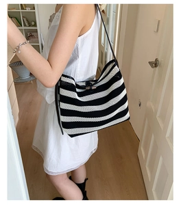 Detail of black and white striped knit hobo bag featuring a secure horn button closure