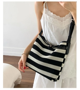 Detail of woven striped tote bag with black leather strap and wooden button closure