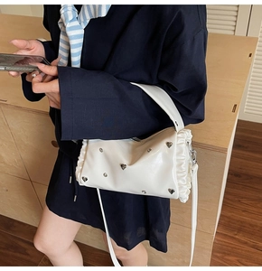 Detailed shot of white tote bag featuring heart rivets and pleated side details