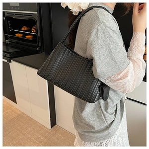 Close-up of black woven shoulder bag featuring intricate Intrecciato pattern and matte finish